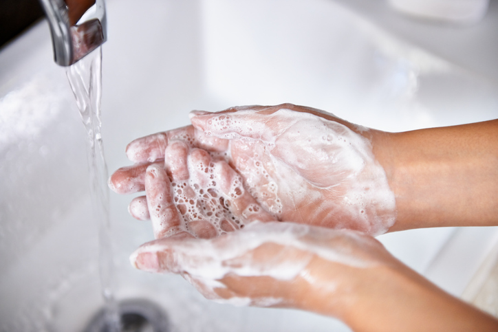 Person washing hands in the sink with soap and water. 